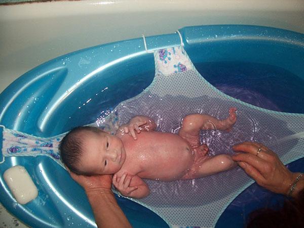 dando banho em um recém-nascido em uma rede